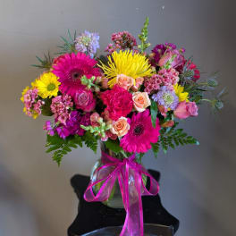 Colorful mixed bouquet in a glass vase with a pink ribbon