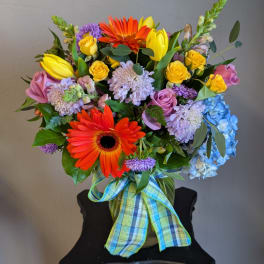 Colorful mixed bouquet with gerbera daisies, roses, tulips, and hydrangea in a vase