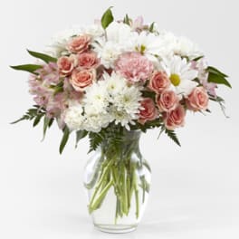 Pink roses and white daisies arranged in a clear glass vase
