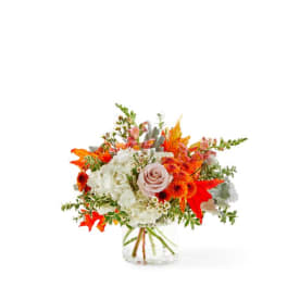 Bouquet of white and orange flowers in a clear glass vase