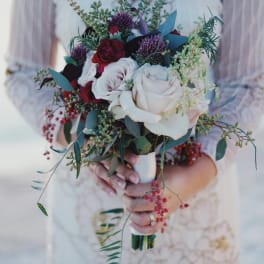 Bride holding a bouquet of white and red roses with greenery