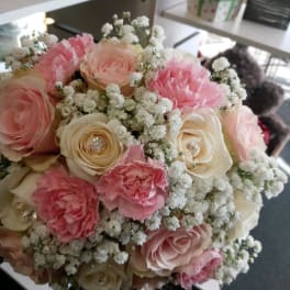 Round bouquet of pink and cream roses with white filler flowers