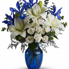 White lilies and roses with blue irises in a cobalt vase