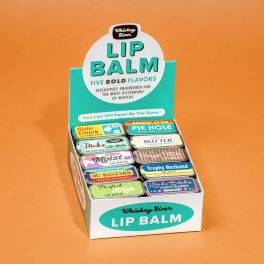 Display box of assorted lip balms on an orange background