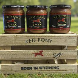 Three jars of Red Pony salsa in a wooden crate outdoors