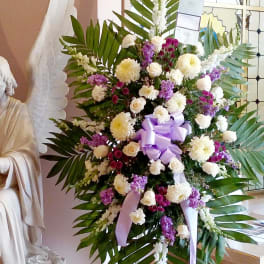 Large standing floral spray with white and purple flowers and a lavender ribbon