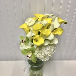 Yellow and white calla lilies with white hydrangea in a glass vase