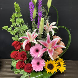 Basket arrangement with roses, lilies, gerberas, and sunflowers
