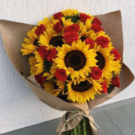 Bouquet of sunflowers and red roses wrapped in brown paper