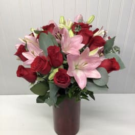 Tall red vase arrangement of red roses and pink lilies