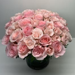 Pink roses arranged in a round bouquet in a dark vase