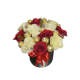 Round box arrangement of red and white roses with gold-wrapped chocolates and red bow
