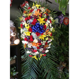 Large multicolored floral standing spray with a blue bow