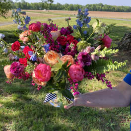 Colorful bouquet of roses, peonies, and blue flowers in a glass vase