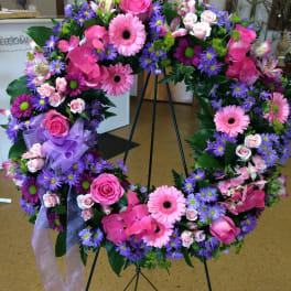 Large pink and purple floral wreath on a stand with ribbon