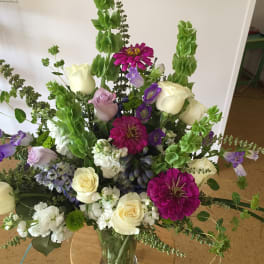 Tall mixed bouquet in a glass vase with white roses and purple flowers