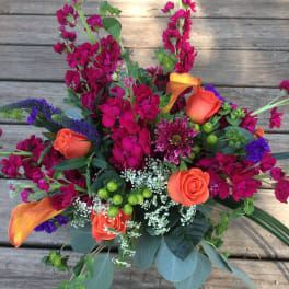 Bright mixed bouquet with orange roses, magenta blooms, and purple accents