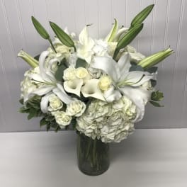 White lilies, calla lilies, and hydrangeas in a glass vase