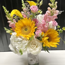 Bouquet of sunflowers, pink roses, and white hydrangeas in a glass vase