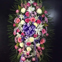Standing floral spray with pink and white flowers and a purple ribbon bow