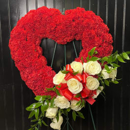 Heart-shaped red carnation wreath with white roses and a red ribbon bow