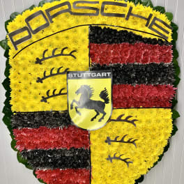Heart-shaped floral tribute in yellow, red, and black with Porsche and Stuttgart emblems