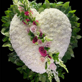 Heart-shaped white floral arrangement with pink roses and greenery