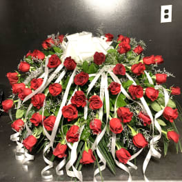 Large arrangement of red roses with white ribbon streamers and a bow