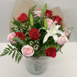 Bouquet of red and pink roses with a white lily in a glass vase