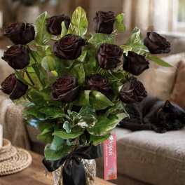 Bouquet of dark roses in a glass vase with a black ribbon