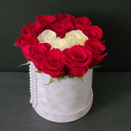 Red and white roses arranged in a white hat box with pearl trim