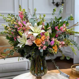 Mixed bouquet of lilies, roses, and pink blooms in a glass vase