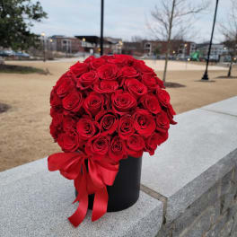 Round bouquet of red roses in a black box with a red ribbon