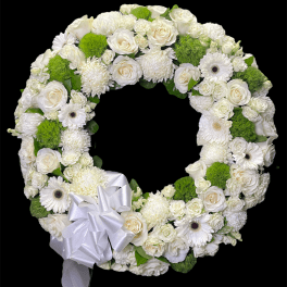 White floral wreath with a satin bow and bright green accents