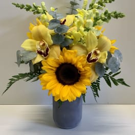 Sunflower and yellow orchid arrangement in a blue vase