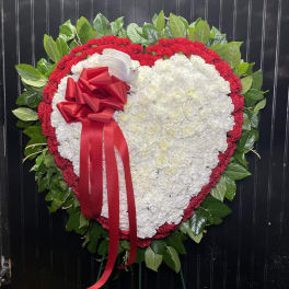Heart-shaped floral wreath with white and red flowers and a red ribbon bow