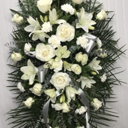White floral standing spray with roses, lilies, and ribbons