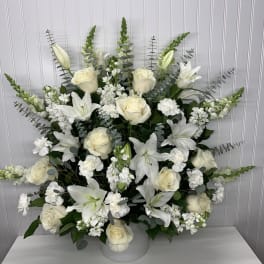 White lilies and roses arranged in a white vase