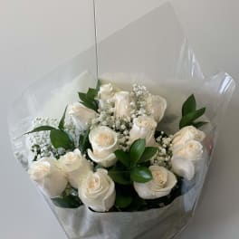 Hand-tied bouquet of white roses with small white filler flowers in clear wrap