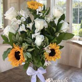 Bouquet of white roses, white alstroemeria, and sunflowers in a glass vase