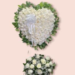 White heart-shaped floral tribute with a white ribbon and green border