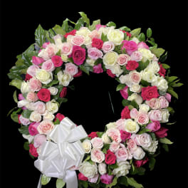Heart-shaped wreath of pink and white roses with a white bow
