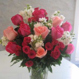 Bouquet of pink, red, and peach roses in a clear glass vase
