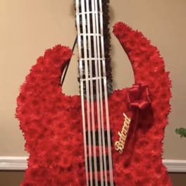 Red floral guitar-shaped arrangement with white strings and a ribbon bow