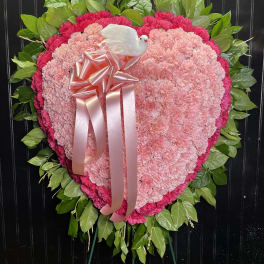 Heart-shaped pink carnation wreath with a ribbon and white dove