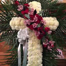 Cross-shaped floral tribute with white carnations, red roses, and pink orchids
