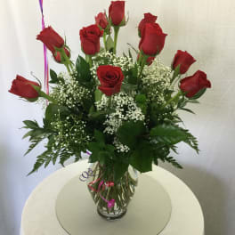 Red roses arranged in a clear glass vase with white filler flowers