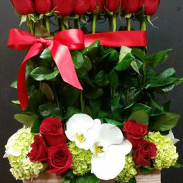 Red roses and white orchids in a gift box with a red ribbon