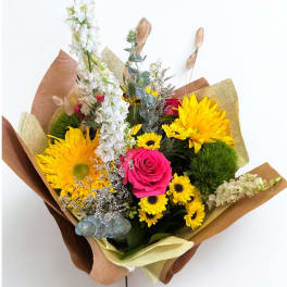 Bouquet with yellow sunflowers, a pink rose, and white flowers wrapped in brown paper