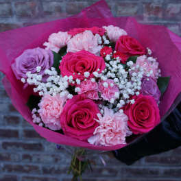 Bouquet of pink and lavender roses with carnations in bright pink wrap